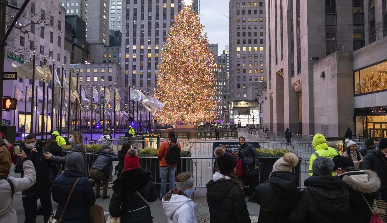 Orang-orang berfoto dengan latar belakang pohon Natal di viewing zone pohon Natal Rockefeller Center di New York, Amerika Serikat (AS) (22/12/2020). Jumlah kasus COVID-19 di negara itu naik menjadi 18.006.061, dengan total 319.190 kematian, hingga Selasa (22/12) pukul 06.22 WIB. (Xinhua/Wang Ying)