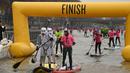 Peserta berkostum Star Wars Stormtrooper mencapai garis finis lomba dayung sambil berdiri pada Nautic SUP Paris di sungai Seine, Paris, Minggu (3/12). Nautic SUP Paris merupakan lomba dayung sambil berdiri terbesar di dunia. (AFP PHOTO/CHRISTOPHE SIMON)