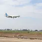 Sebuah pesawat melintas di atas proyek pembangunan runway dan taxiway 3 di Bandara Soekarno-Hatta, Tangerang, Kamis (21/6). Pembebasan lahan pembangunan runway di bandara Soetta sisi utara sudah mencapai 70 persen. (Liputan6.com/Angga Yuniar)