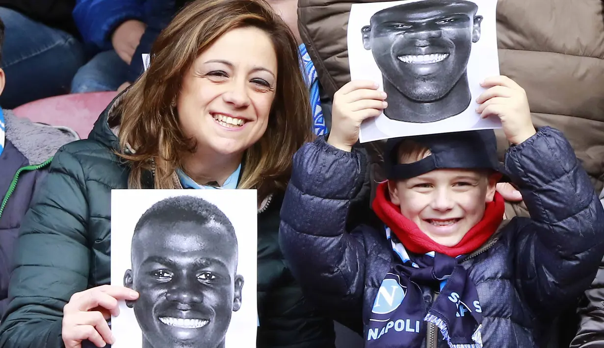 Ibu dan anak memegang poster pemain Napoli, Kalidou Koulibaly pada laga  Serie A Liga Italia di San Paolo stadium, Minggu (7/2/2016).  Kalidou mendapat dukungan atas tindakan rasis dari fans Lazio. (AFP/Carlo Hermann)