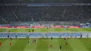 Para pemain melakukan pemanasan di dekat Replika Tembok Berlin bertuliskan "Bersatu menentang tembok.Bersatu untuk Berlin" berdiri jelang pertandingan Hertha Berlin melawan RB Leipzig di Stadion Olimpiade, Berlin (9/11/2019). (AFP/Odd Andersen)