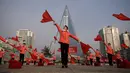 Kelompok Serikat Wanita Sosialis mengibarkan bendera saat melakukan propaganda di depan Hotel Ryugyong, Pyongyang, Korea Utara, Sabtu (9/3). Mereka mengibar-ngibarkan bendera sambil menyanyikan lagu-lagu patriotik selama jam sibuk. (Ed Jones/AFP)