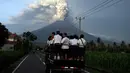 Para pelajar berdiri di sebuah mobil untuk pergi ke sekolah di tengah erupsi Gunung Agung di Karangasem, Bali, Selasa, (28/11). Erupsi Gunung Agung yang masih terjadi menyebabkan Bandara Ngurah Rai ditutup. (AP Photo/Firdia Lisnawati)