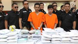 Petugas menunjukkan barang bukti beserta tersangka kasus penyelundupan ekstasi di Mabes Polri, Jakarta, Selasa (1/8). Polri dan Bea Cukai mengungkap penyelundupan 1,2 juta butir ekstasi dari Belanda senilai Rp600 miliar. (Liputan6.com/Immanuel Antonius)
