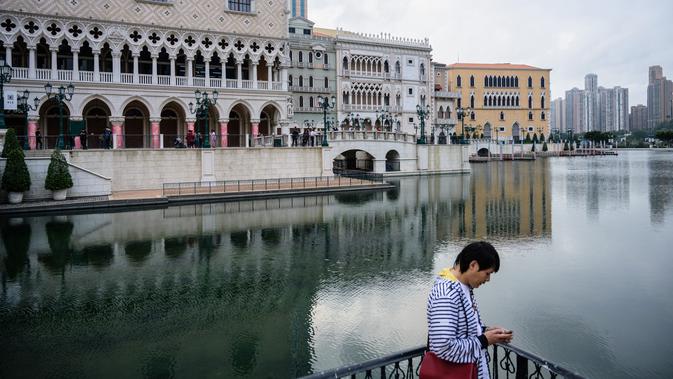 Seorang pria memakai ponselnya di luar resor kasino The Venetian, Macau, 5 Maret 2019. Pada sensus 2016, penduduk Macau berjumlah sekitar 600 ribu orang. (Anthony Wallace/AFP)