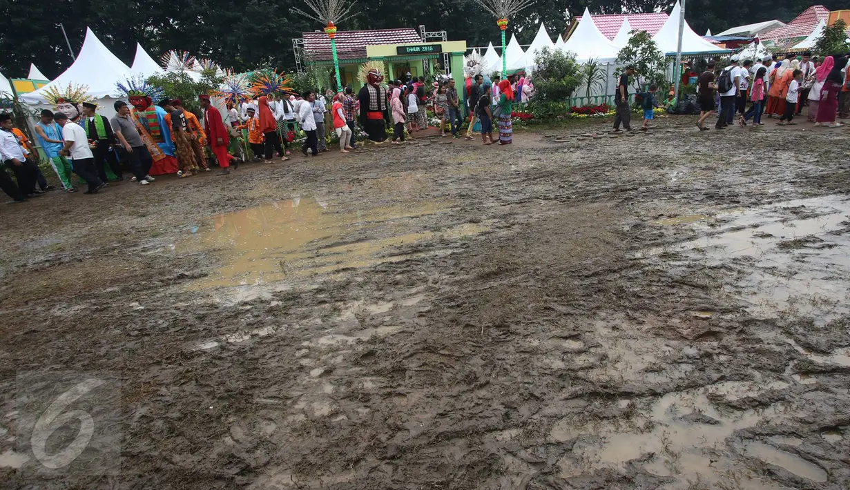 Pengunjung menghindari jalan yang becek pada Festival Lebaran Betawi IX, Jakarta, (14/8). Festival diramaikan dengan rumah adat Betawi dari masing-masing pemkot  administrasi Jakarta serta Kabupaten Kepulauan Seribu. (Liputan6.com/Immanuel Antonius)