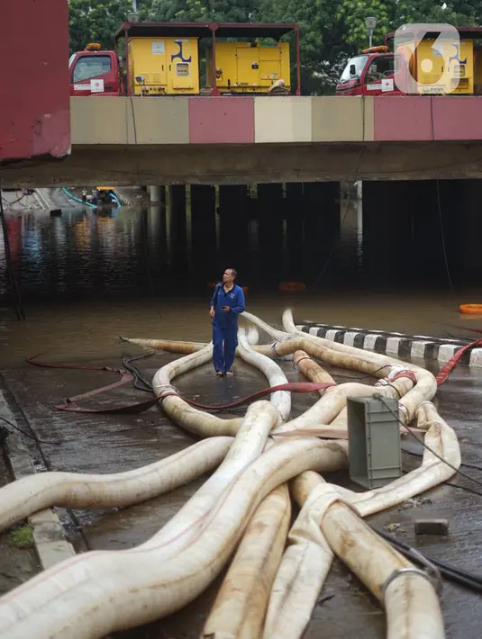 Petugas memasang pompa penyedot air di banjir yang menggenangi underpass Kemayoran, Jakarta, Senin (3/2/2020). Curah hujan tinggi menyebabkan banjir yang menggenangi kawasan tersebut lama surut sehingga menutup arus lalu lintas. (Liputan6.com/Immanuel Antonius)