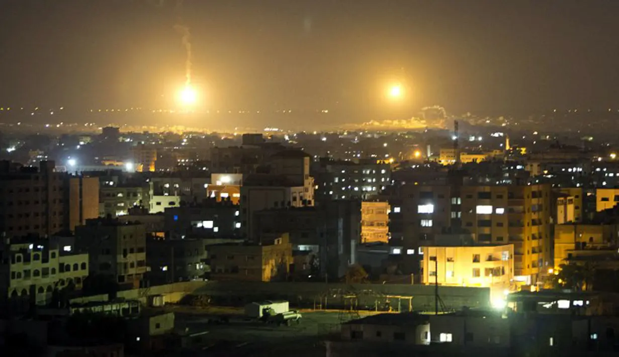 Api dari rudal militer Israel menerangi langit kota Gaza. Militer Israel kembali melakukan serangan udara ke kota Gaza, Palestina, (12/7/2014). (AFP PHOTO/Mahmud Hams)