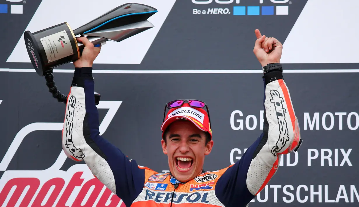 Pembalap Repsol Honda Tim MotoGP Marc Marquez mengangkat trofi usai menjuarai Grand Prix MotoGP di Sirkuit Sachsenring, Jerman, Minggu (12/7/2015). Pembalap asal Spanyol ini menduduki peringkat pertama pada seri sembilan ini. (REUTERS/Hannibal Hanschke)