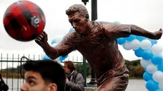 Seorang anak bermain bola di depan patung perunggu Lionel Messi yang baru diresmikan di pusat kota Buenos Aires, Argentina, Selasa (28/6). Patung tersebut guna membujuk Messi membatalkan keputusan pensiun yang sudah diambilnya. (REUTERS/Marcos Brindicci)