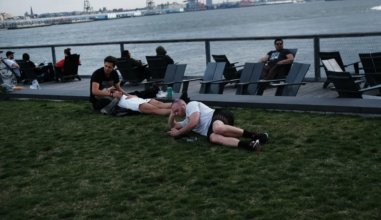 Orang-orang beristirahat saat menikmati musim semi yang hangat di tepi air di Manhattan di New York City (8/4). Sebagian besar Pantai Timur mengharapkan suhu hangat terus sepanjang minggu. (Spencer Platt/Getty Images/AFP)