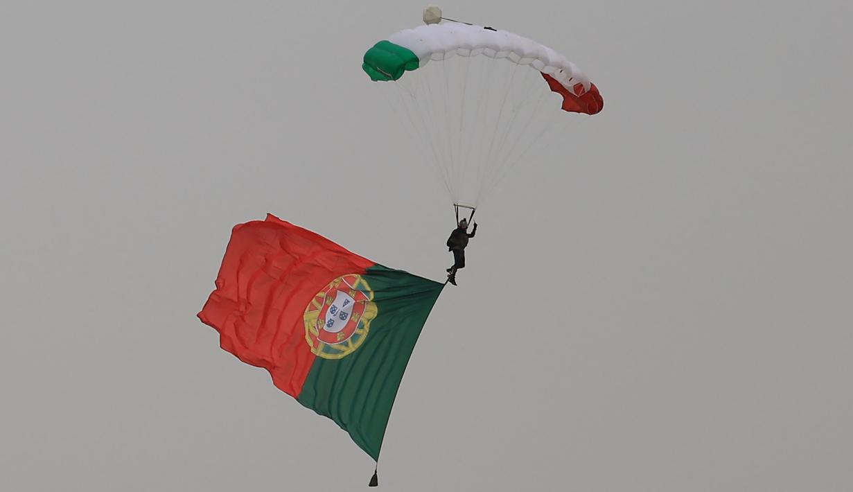 Bendera Portugal dikibarkan melalui parasut di atas Sirkuit Internasional Algarve, Portimao, Portugal, jelang dimulainya balapan utama MotoGP Portugal 2024, Minggu (24/3/2024) malam WIB. (AFP/Patricia De Melo Moreira)