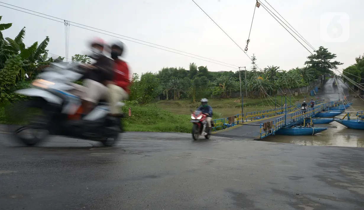 Pengendara sepeda motor melintasi jembatan perahu di atas Sungai Citarum, Karawang, Jawa Barat, Sabtu (20/11/2021). Tarif sekali melewati jembatan perahu ini dipatok Rp 2.000 per sepeda motor dan Rp 1.000 bagi pejalan kaki. (merdeka.com/Imam Buhori)