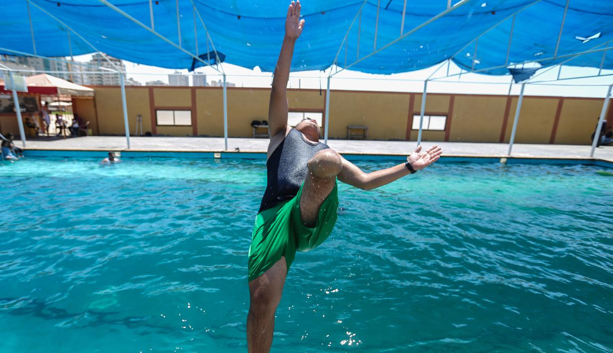 Pemuda Palestina yang diamputasi melompat ke kolam renang selama sesi pelatihan oleh instruktur Majdi al-Tatar di Kota Gaza (30/7/2019). Tatar, yang kehilangan kaki kanannya akibat kecelakaan pada masa kecilnya, melatih warga Palestina yang diamputasi selama konflik dengan Israel. (AFP Photo/Mahmud
