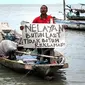 Seorang warga kampung nelayan berunjukrasa  Bulak Cumpat dan Nambangan menolak rencana reklamasi laut di kawasan Pantai Kenjeran Surabaya, Jumat (21/1). (Antara)