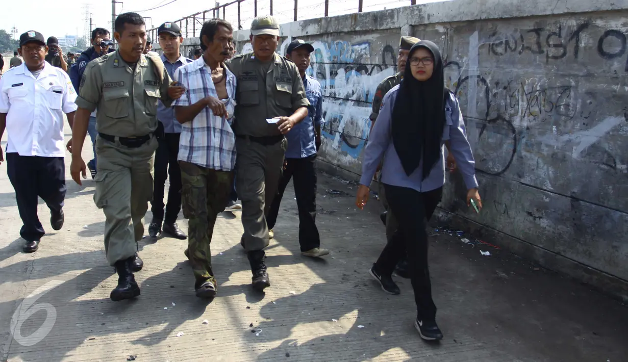 Seorang pria dibawa petugas Dinas Sosial saat penertiban gubuk liar di Jalan Inspeksi Kanal Banjir Barat (KBB), Rabu (13/7). Penertiban dilakukan lantaran gubuk liar itu berdiri di bahu jalan dan mengganggu ketertiban umum. (Liputan6.com/Gempur M Surya)