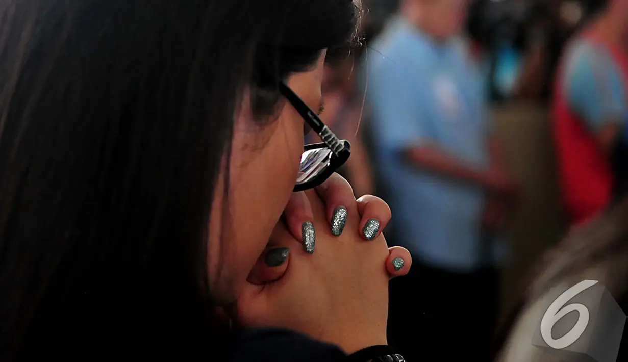 Salah satu keluarga penumpang pesawat AirAsia QZ8501 khusyuk berdoa saat misa bersama di Bandara Juanda, Surabaya, Rabu (31/12/2014). (Liputan6.com/Johan Tallo)