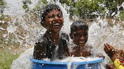 Dua anak berendam mendinginkan tubuhnya saat gelombang panas menerjang di pinggiran Ahmedabad, India, (28/5/2015). Gelombang panas di India telah menewaskan sedikitnya 1.371 karena suhu meningkat di atas 47 Celcius. (REUTERS/Amit Dave)