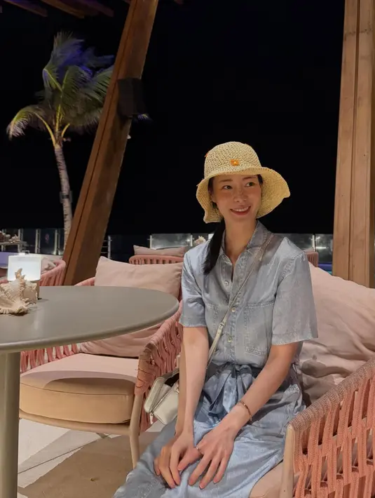 Mengenakan topi pantai jerami, Lim Ji Yeon mengenakan long dress denim dengan belt pita sambil membawa sling bag silver.  [@limjjy2]