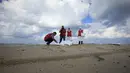 Kelompok Bulan Sabit Merah Libya memeriksa jenazah, diduga imigran  yang tewas usai kapal mereka tenggelam, di pantai Khoms, sebelah timur Tripoli, Minggu (25/10). Sedikitnya 40 jasad telah ditemukan di pantai Libya. (REUTERS/Ismail Zitouny)
