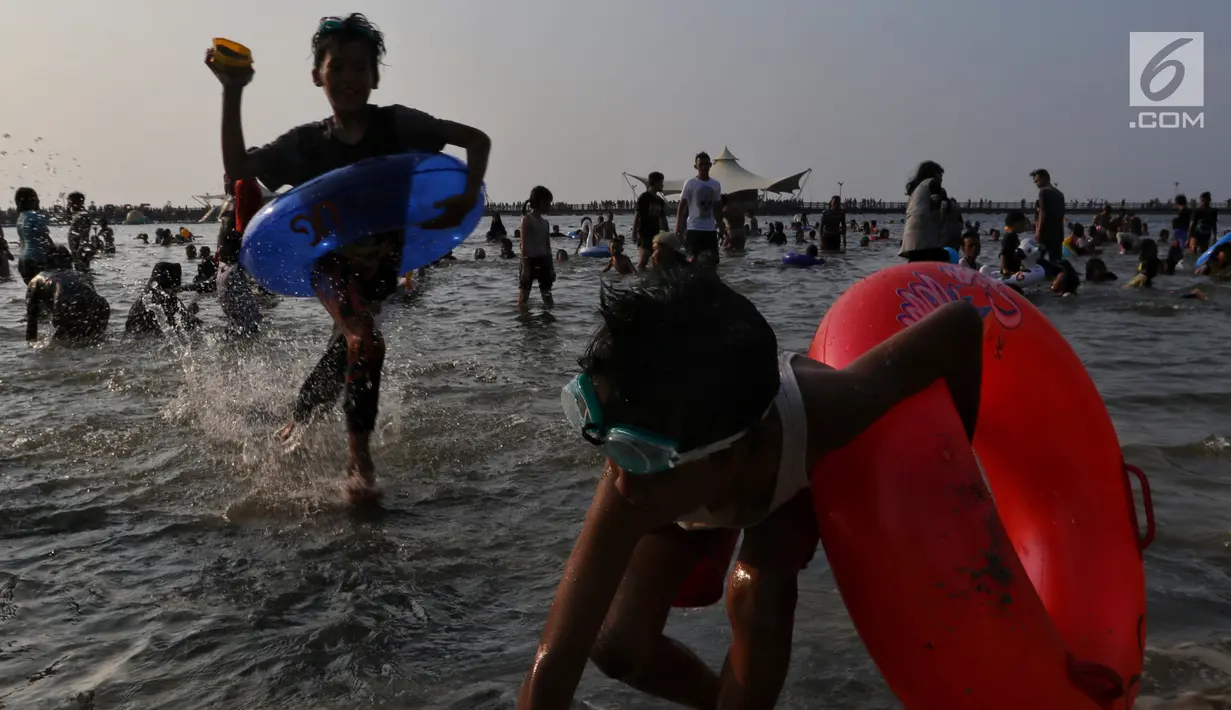Pengunjung bermain dan berenang di kawasan Beach Pool, Taman Impian Jaya Ancol, Jakarta, Kamis (6/6/2019). Hari kedua Lebaran banyak dimanfaatkan warga untuk berlibur dan berekreasi bersama keluarga atau kerabat dengan mengunjungi pantai Ancol. (Liputan6.com/Johan Tallo)