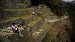 Wisatawan bersantai di tebing benteng Inca Machu Picchu, Peru, Rabu (12/8/2015). Machu Picchu sering juga disebut Kota Inca yang hilang yang terletak di wilayah pegunungan pada ketinggian sekitar 2.350 m di atas permukaan laut. (REUTERS/Pilar Olivares)
