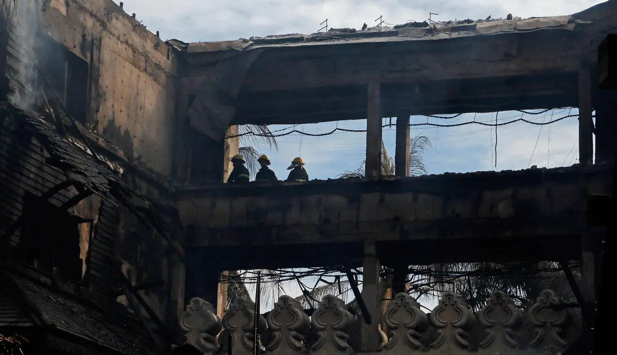 Petugas pemadam kebakaran memeriksa Hotel Istana Kandawgyi usai kebakaran di Yangon, Myanmar (19/10). Api telah melahap hotel bintang lima yang sering dikunjungi wisatawan asing di kota Yangon, Myanmar. (AP Photo/Thein Zaw)