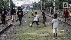 Anak-anak bermain bola di tengah perlintasan kereta api kawasan Ancol, Jakarta Utara, Kamis (19/5/2022). Data Kementerian Kesehatan pada 17 Mei 2022 mengungkapkan, enam orang meninggal karena diduga terjangkit hepatitis akut yang belum diketahui penyebabnya alias hepatitis misterius. (Liputan6.com/Johan Tallo)