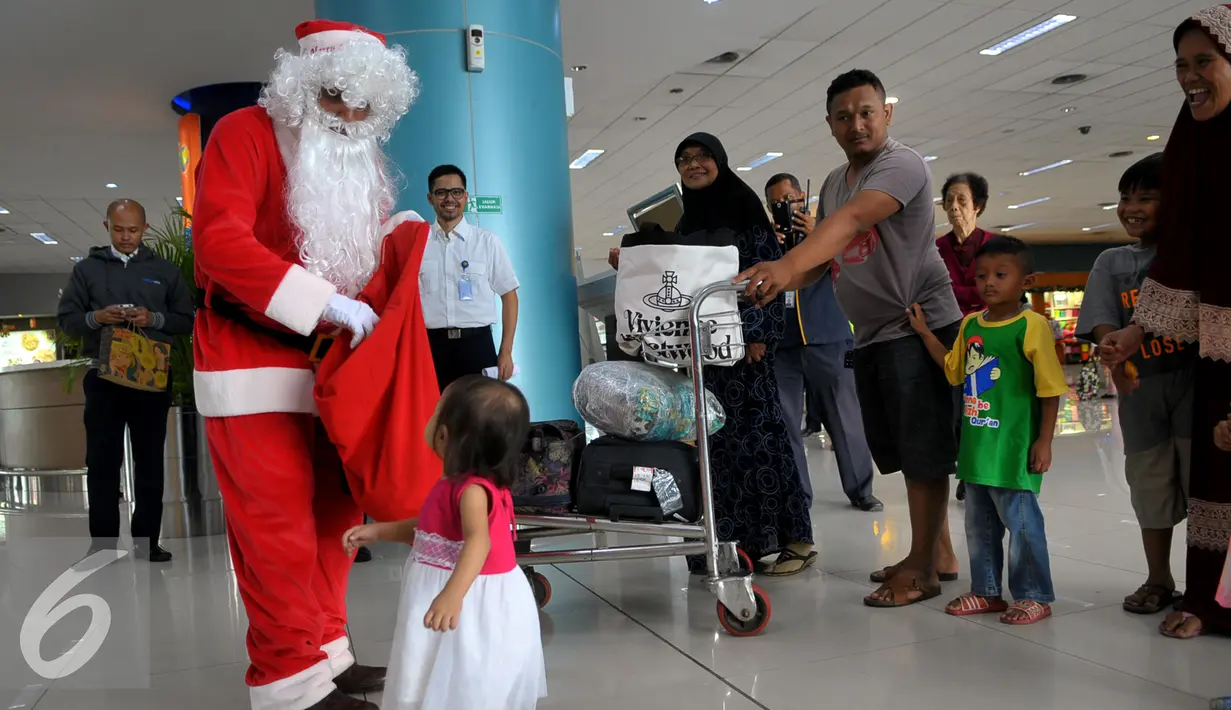 Santa Claus saat ingin memberikan hadiah kepada seorang anak di Bandara Soekarno Hatta, Tangerang, Banten, Selasa (22/12). Sejumlah orang berkostum santa claus membagikan coklat kepada penumpang yang berada dibandara. (Liputan6.com/Faisal R Syam)