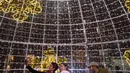Keluarga berselfie di bawah lampu Natal yang menghiasi jalan Santa Cruz de Tenerife di pulau Canary Tenerife, Spanyol (19/12). Menyambut Natal kota Tenerife memasang lampu warna-warni untuk menghiasi sejumlah jalanan. (AFP Photo/Desiree Martin)