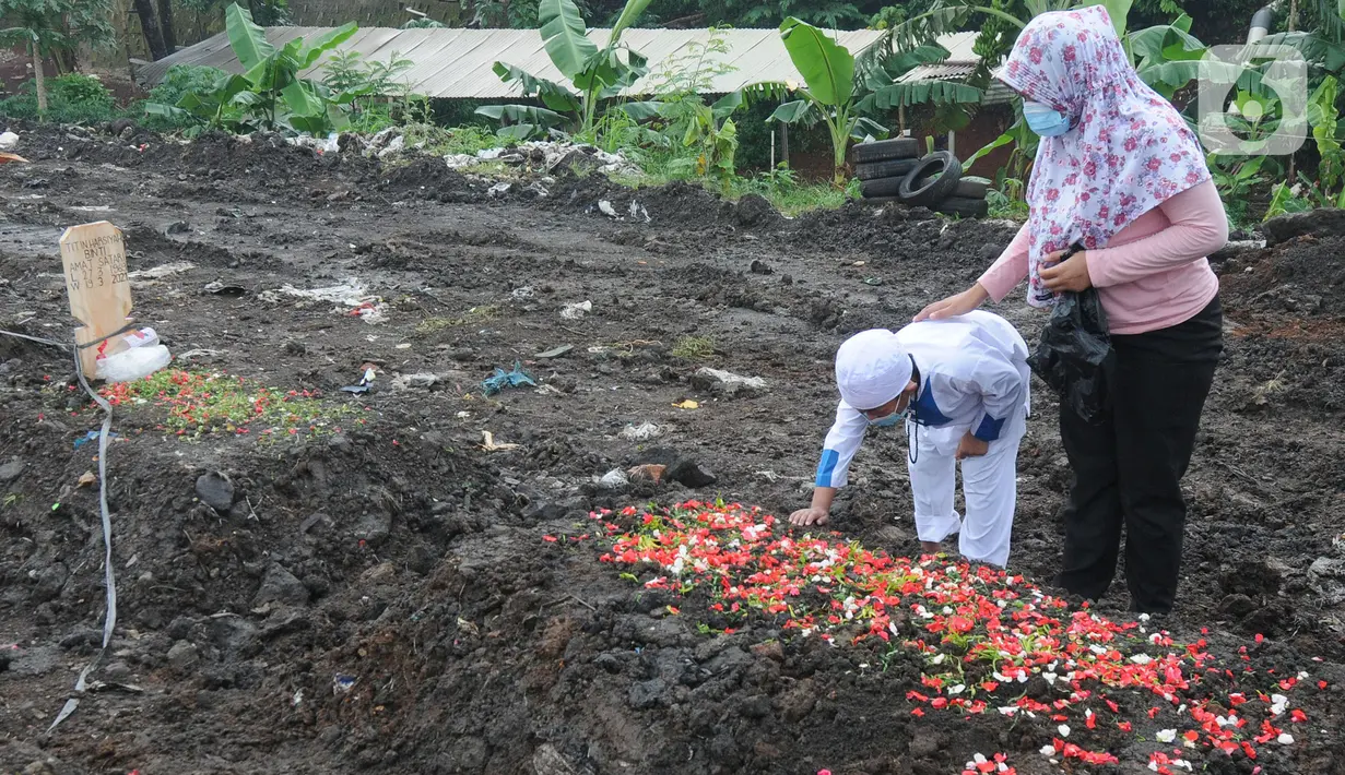Keluarga berdoa depan pusara makam korban Covid-19 di TPU Srengseng Sawah 2, Jakarta Selatan, Jumat (19/3/2021). Seminggu terakhir intensitas pemakaman korban Covid-19 menurun drastis sebesar rata-rata 20 jenazah/minggu dibandingkan sebelumnya rata-rata 35 jenazah/minggu. (merdeka.com/Arie Basuki)