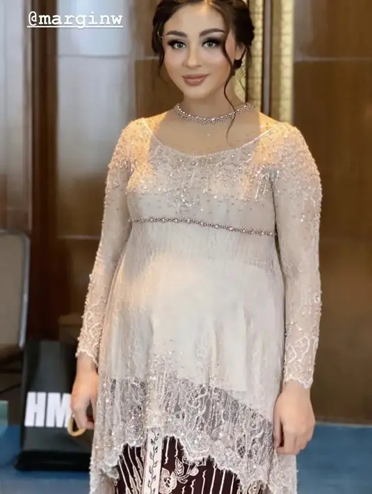 Margin tampil dengan kebaya berpayet warna nude model kurung, padukan dengan kain lilit cokelat.