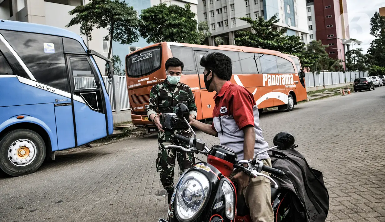 Petugas kurir JNE saat mengantarkan paket ke anggota TNI yang sedang bertugas di Wisma Atlet Pademangan, Jakarta, Selasa (29/12/2020). Beralihnya warga ke belanja melalui e-commerce karena tidak harus keluar rumah guna mencegah penularan virus corona COVID-19. (merdeka.com/Iqbal S. Nugroho)