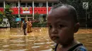 Anak-anak melintasi banjir yang melanda kawasan bantaran kali Cisadane, Tangerang, Jumat (26/4). Banjir kiriman setinggi 2 meter sempat melanda kawasan akibat curah hujan yang tinggi di bogor membuat derasnya air mengalir jauh sampai ke tempat ini. (Liputan6.com/Johan Tallo)