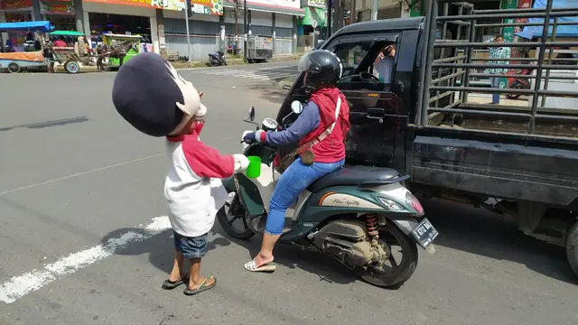 Seorang pengamen boneka tengah menanti belas kasian pengguna jalan di perempatan lampu merah Toserba Asia, Garut, Jawa Barat.