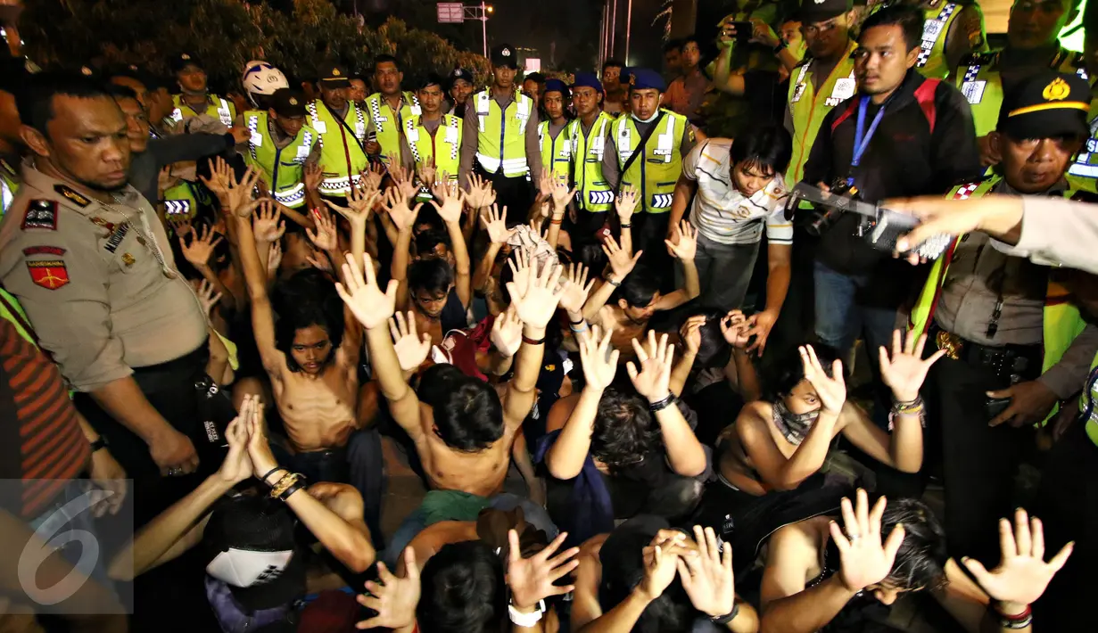 Polisi mengamankan puluhan remaja yang diduga sebagai The Jak Mania di Jalan Sudirman, Jakarta, Minggu (18/10).  Mereka disuruh telanjang dada dan kemudian diangkut ke Polda Metro Jaya usai terlibat bentrokan dengan polisi.(Liputan6.com/Immanuel Antonius)