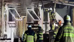 Petugas pemadam kebakaran mengecek tempat pengungsi di Fagersjo yang terbakar, Stockholm, Swedia pada Minggu (16/10) malam. (REUTERS/TT News Agency / Johan Nilsson)