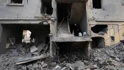 Serangan udara Israel menyasar sejumlah wilayah di Lebanon, terutama selatan dan pinggiran Kota Beirut. Tampak dalam foto, seorang wanita menaiki tangga di sebuah bangunan yang hancur akibat serangan udara Israel di kota pelabuhan Tyre, Lebanon selatan, Kamis, 26 Maret 2026. (AP Photo/Hussein Malla)
