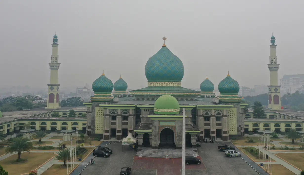 Gambar udara menunjukkan sebuah masjid ketika kabut asap pekat menyelimuti Pekanbaru, Riau, Minggu (15/9/2019). Menurut Data AirVisual, hingga pagi tadi kualitas udara Riau menunjukkan indeks tidak sehat dengan parameter Air Quality Index (AQI) atau indeks kualitas udara 161. (ADEK BERRY/AFP)
