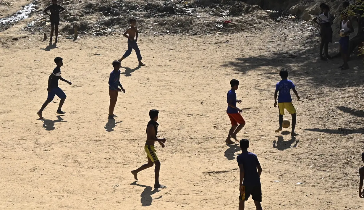 Anak-anak pengungsi Rohingya bermain sepak bola di kamp pengungsi Kutupalong di Ukhia (22/3/2022). Ratusan ribu orang Rohingya melarikan diri dari Myanmar setelah tindakan keras tahun 2017, yang menjadi subjek kasus genosida di pengadilan tertinggi PBB di Den Haag. (AFP/Munir Uz Zaman)