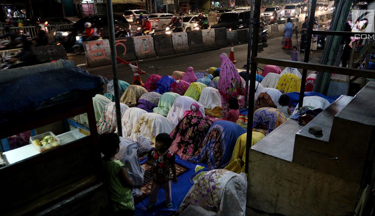 Pemandangan saat jemaah melaksanakan salat tarawih hingga ke badan jalan akibat melubernya Musala Miftahul Jannah di Kawasan Pasar Gembrong, Jakarta, Kamis (17/5). (Liputan6.com/JohanTallo)