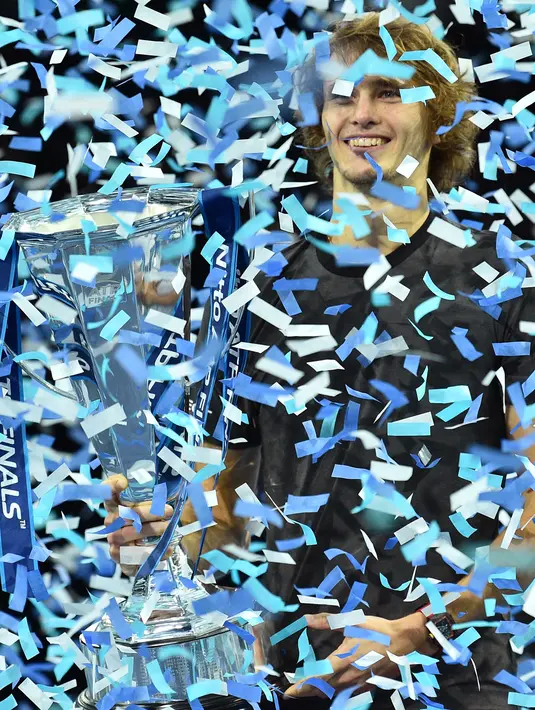 Petenis Jerman, Alexander Zverev memegang trofi setelah mengalahkan Novak Djokovic pada laga puncak ATP Finals 2018 di O2 Arena, London, Senin (19/11). Zverev mengalahkan petenis nomor satu dunia dalam dua set langsung 6-4, 6-3. (Glyn KIRK / AFP)