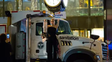 Penyanyi Lady Gaga berbusana serba hitam dan membawa bendera AS berunjuk rasa di depan Trump Tower, New York City, AS (9/11). Sebagai bentuk protesnya, Gaga mengangkat poster bertuliskan “Love Trumps Hate.”( AFP PHOTO / Dominick Reuter)