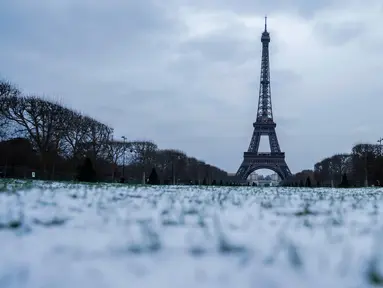 Foto yang diambil di Champ de Mars di Paris pada tanggal 9 Januari 2024, menunjukkan ruang terbuka hijau publik yang luas yang tertutup salju dan Menara Eiffel. (Ludovic MARIN/AFP)