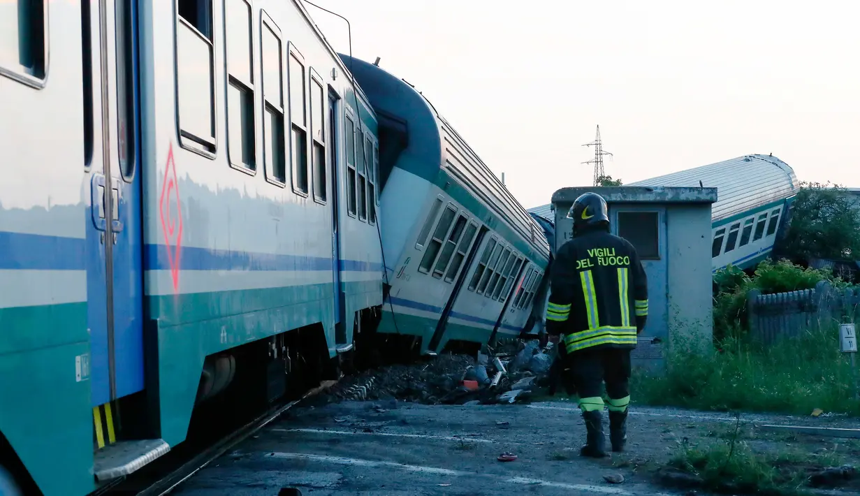 Petugas berjalan dekat rangkaian kereta api yang mengalami kecelakaan dan keluar jalur di dekat Turin, Italia, Kamis (24/5). Kecelakaan terjadi ketika rangkaian kereta api menghantam truk besar yang berhenti di sebuah perlintasan. (AP/Antonio Calanni)
