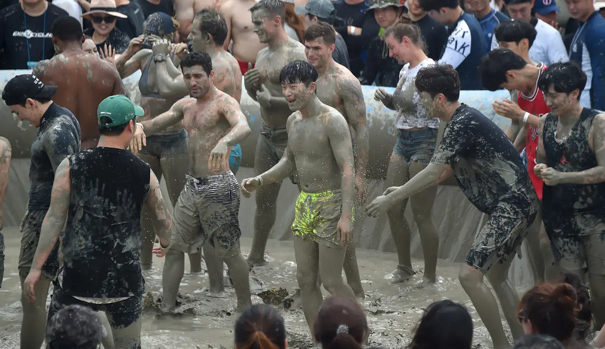 Wisatawan bermain di kolam lumpur selama Boryeong Mud Festival atau Festival Lumpur Boryeong di pantai Daecheon, Korea Selatan, Sabtu (20/7/2019).  Festival yang berlangsung dari 19 - 28 Juli 2019 ini pertama kali diadakan pada 1998 untuk memperkenalkan kosmetik dari lumpur Boryeong. (Minji SUH/AFP)
