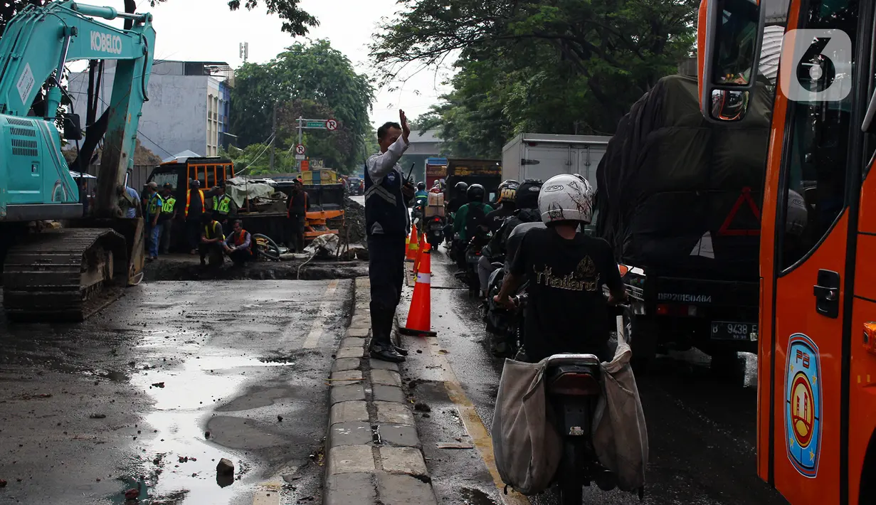 Petugas Dishub mengatur lalu lintas saat sistem rekayasa lalu lintas one way atau satu arah di ruas Jalan Daan Mogot arah Tangerang Kota, Senin (13/1/2020). Penerapan ini dilakukan karena kemacetan akibat perbaikan jalan ambles di kawasan Daan Mogot. (merdeka.com/Magang/Muhammad Fayyadh)