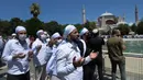 Umat Muslim berdoa saat menunaikan salat Jumat dengan latar belakang situs bersejarah Hagia Sophia di distrik bersejarah Sultanahmet di Istanbul, Jumat (24/7/2020). Hari ini, Hagia Sophia menyambut umat Islam melaksanakan salat Jumat pertama dalam 86 tahun.(AP Photo/Yasin Akgul)