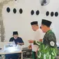 Pengasuh Ponpes Bumi Damai Al Mustawa, KH Muzayin ketika memperlihatkan kepada Anggota DPRD Jawa Tengah, H Abdullah Aminuddin saat santri alumni pesantren setempat memproses pembuatan peci hitam. (Liputan6.com/Ahmad Adirin)