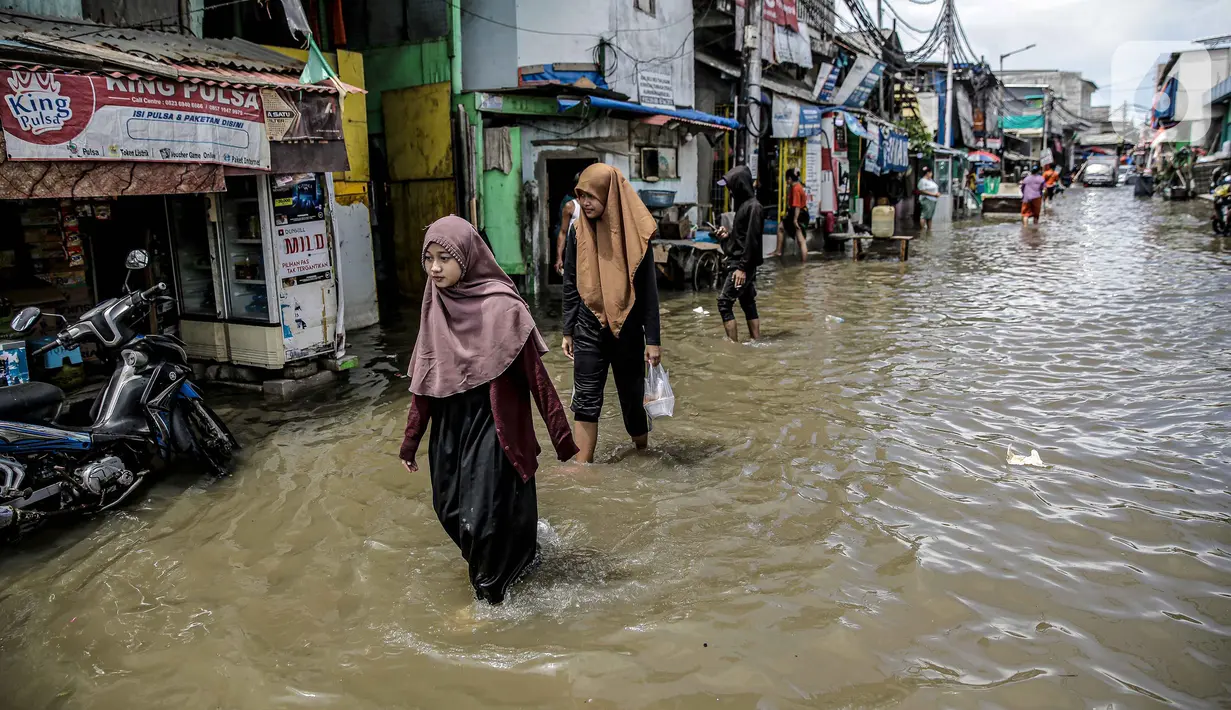 Warga berjalan melewati banjir rob di kawasan Muara Angke, Jakarta, Selasa (9/11/2021). Badan Penanggulangan Bencana Daerah (BPBD) DKI Jakarta memperkirakan puncak musim hujan dan potensi rob di Ibu Kota terjadi pada Januari hingga Februari 2022. (Liputan6.com/Faizal Fanani)